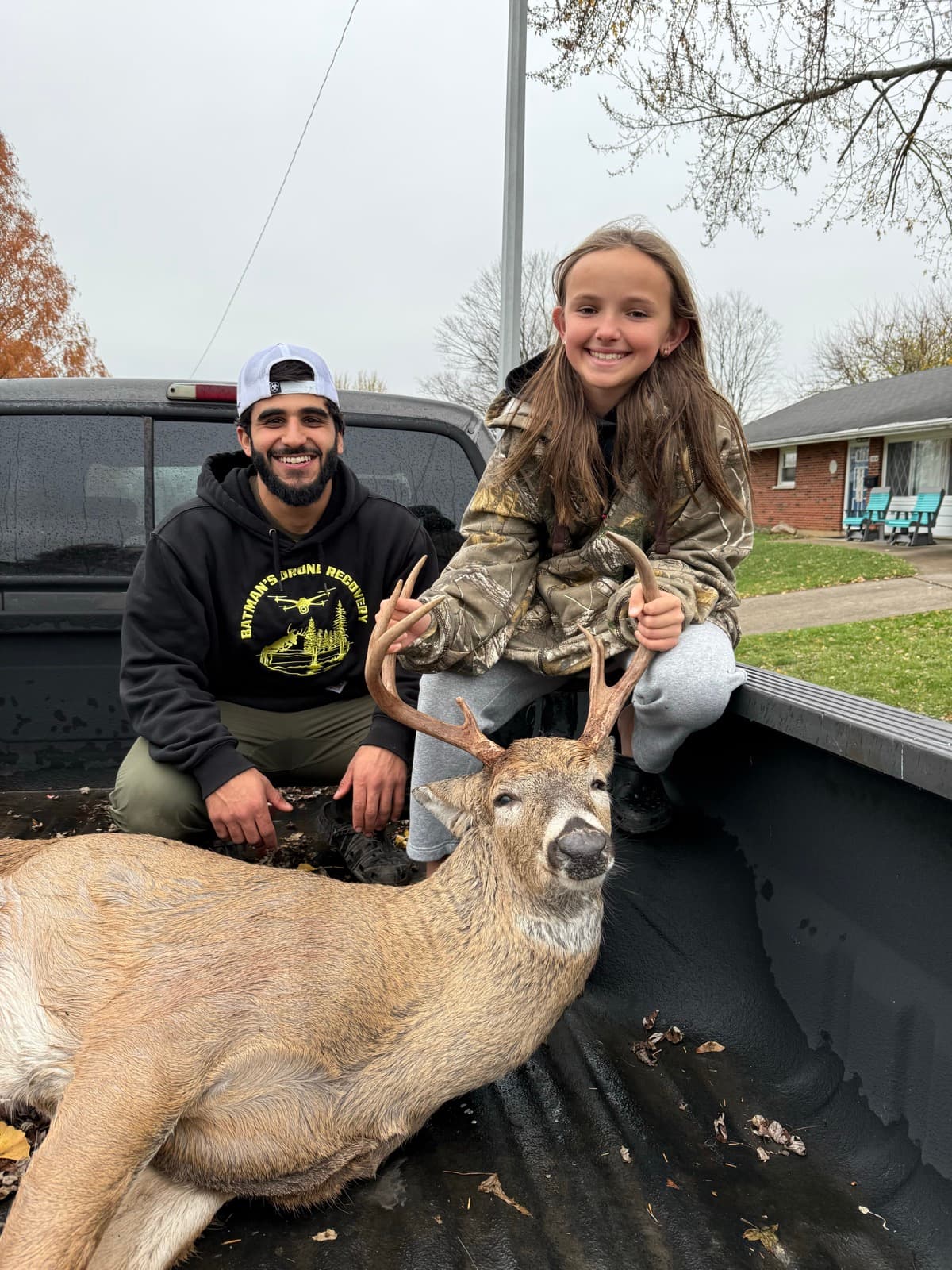 Young hunter and crew member with a buck in the truck bed